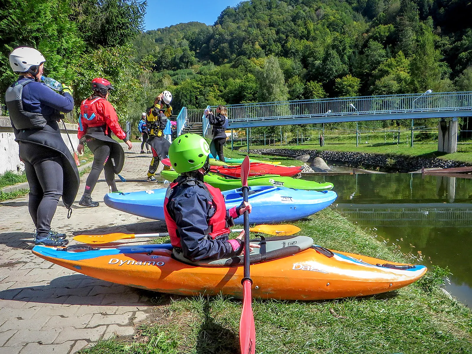 Kursanci z kolorowymi kajakami na brzegu toru kajakowego Wietrznice